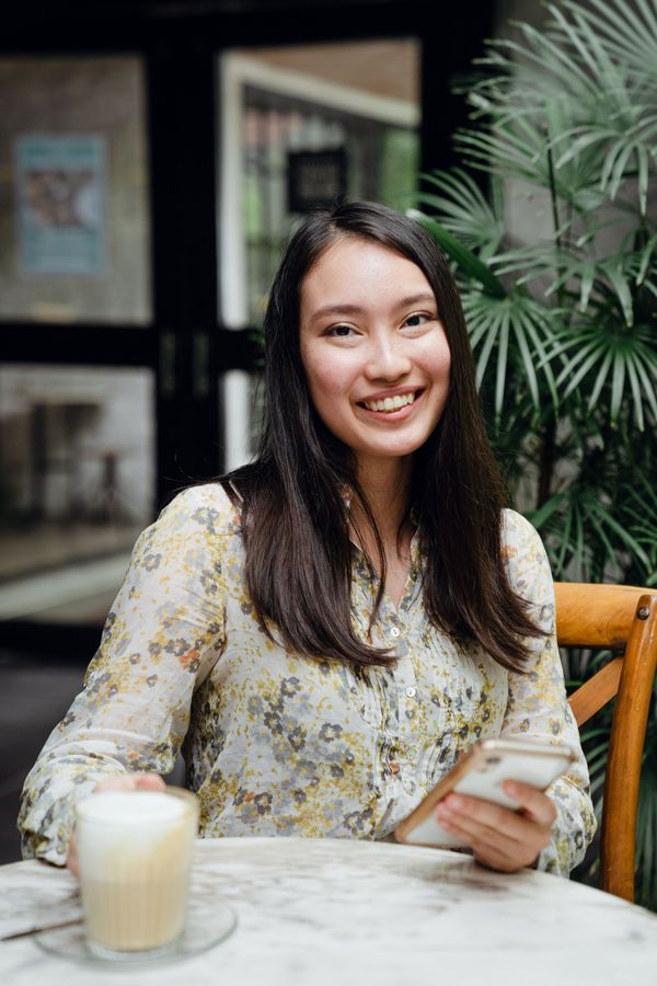 Young woman smiling with her phone over coffee at a cafe